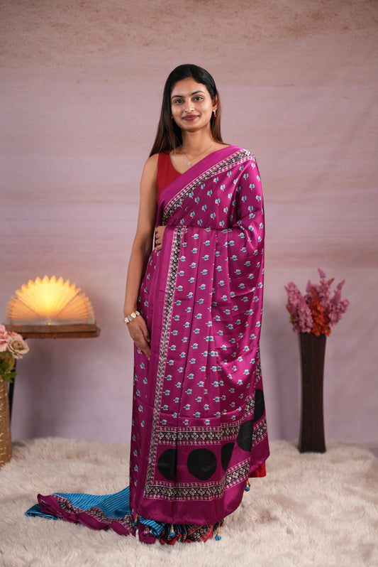 Purple and Sky Blue colour satin modal saree featuring stripes on the body, Ajrakh prints on the border & polka dots with jhumka tassels on the pallu, paired with a matching Ajrakh printed blouse piece.
