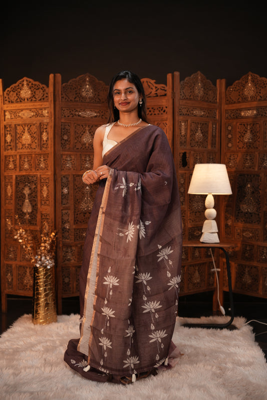 Mocha colour Semi Linen saree featuring plain & lotus print, Bavanchi border & same print on Pallu, comes with contrast colour blouse piece.