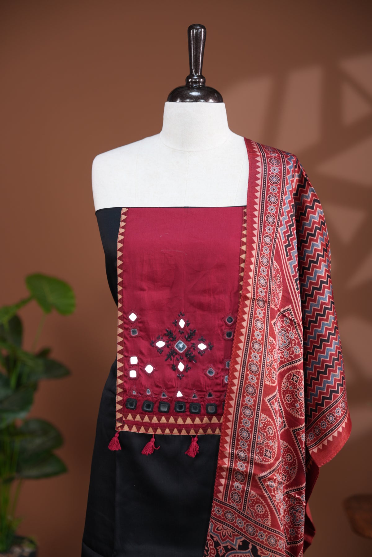 Black colour Jam Satin salwar material, Plain body with mirror & thread work on neck portion, matching bottom and Dupatta with ajrak print.