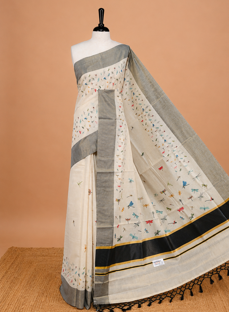 Cream Colour tissue Kerala Saree Featuring Plain Body ,Complemented By Black Zari With Dragonfly Printed   Border ,Enhance By A  Black With Gold Zari  Pallu ,Paired With A Matching Blouse Piece.