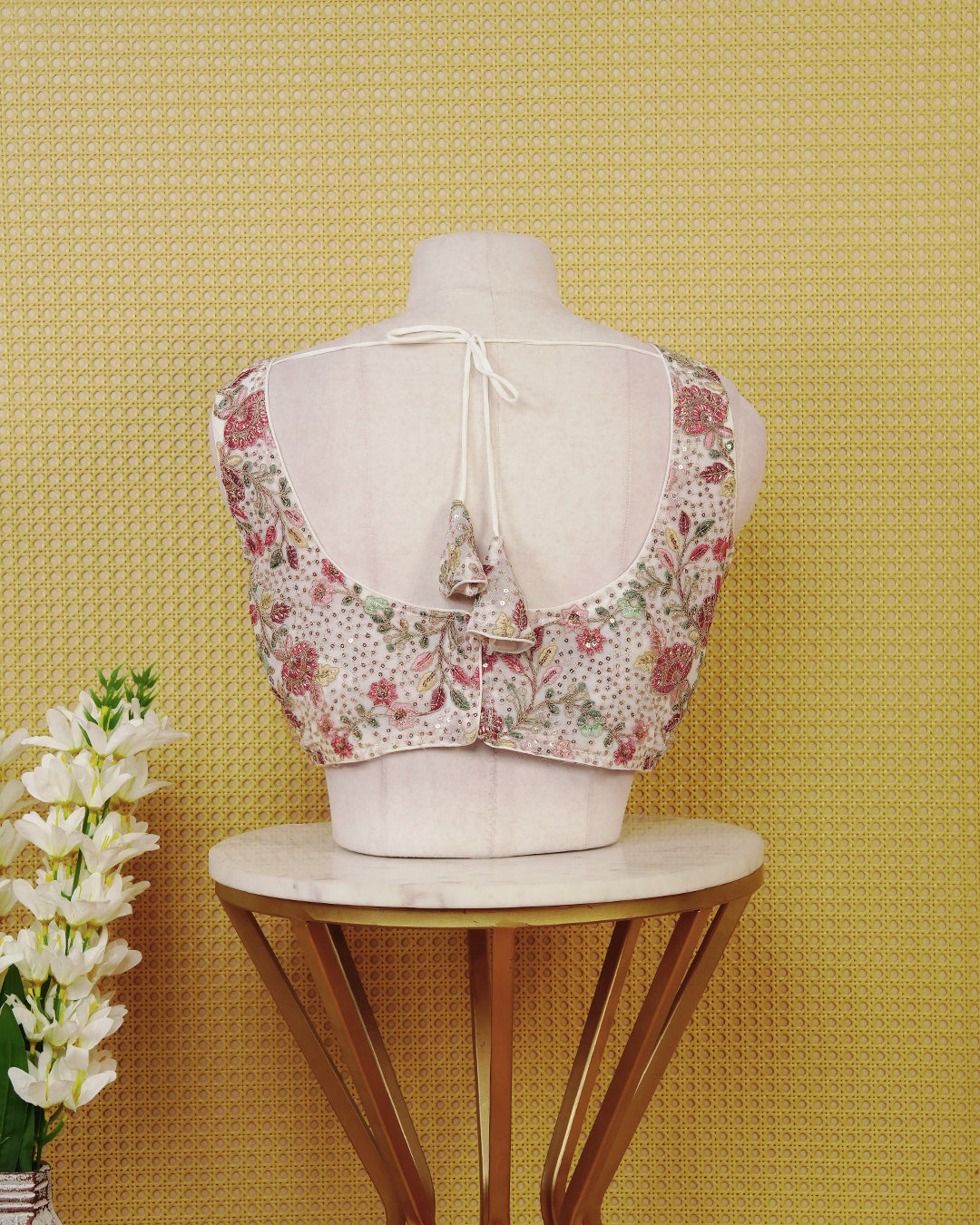 Off White colour Embroidered Sleeveless Blouse Featuring A Stylish V-Neck, Intricate Floral Embroidery With Sequin Detailing, And A Comfortable Tailored Fit.