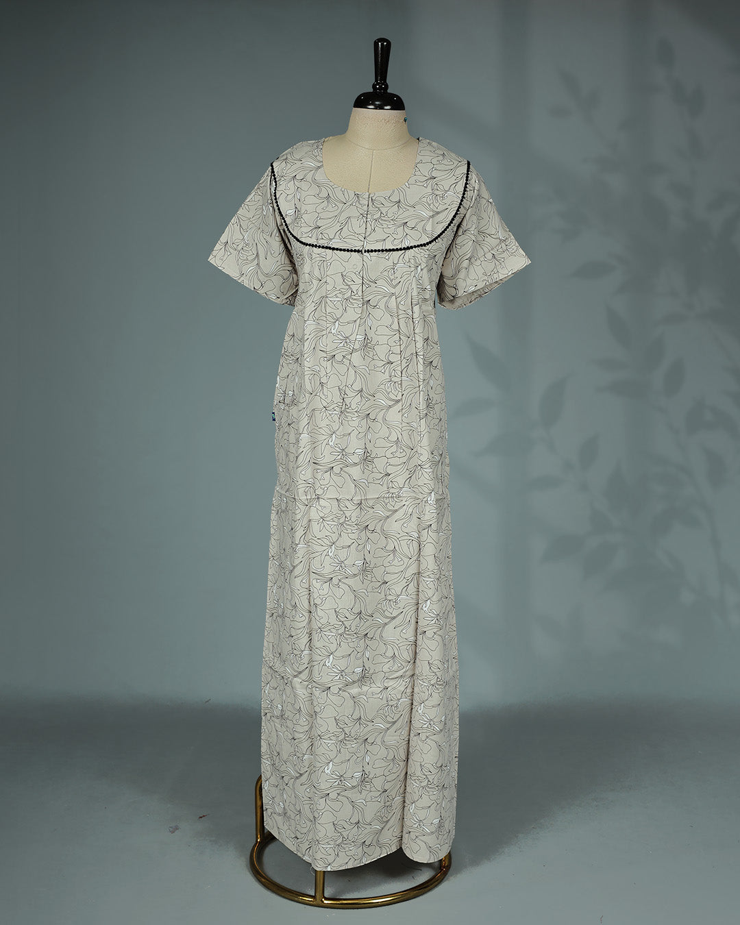 Beige & Black colour floral kodi printed nighty featuring a graceful round yoke with delicate black lace trim, soft front pleats, short sleeves and a relaxed full-length  for breathable comfort and timeless everyday style.