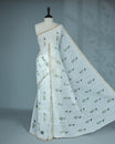 Off-white linen saree featuring beautiful Blue floral and leafy prints on the body, complemented by a tissue piping border and a contrasting pallu. Paired with a matching blouse piece.