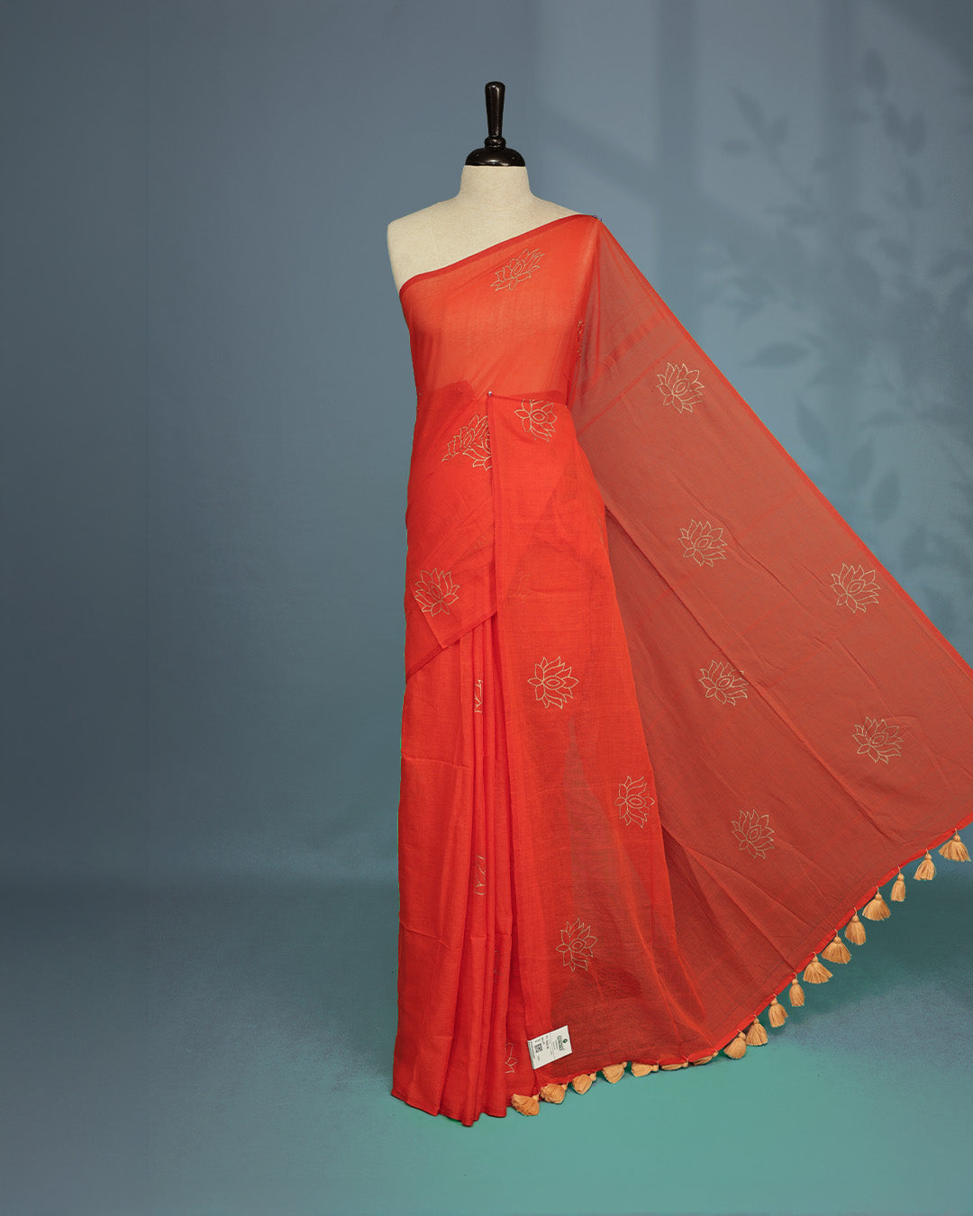 Orange colour pure mul cotton saree featuring Minimal Lotus Print on body, Clean Borderless design, elegant tassels.