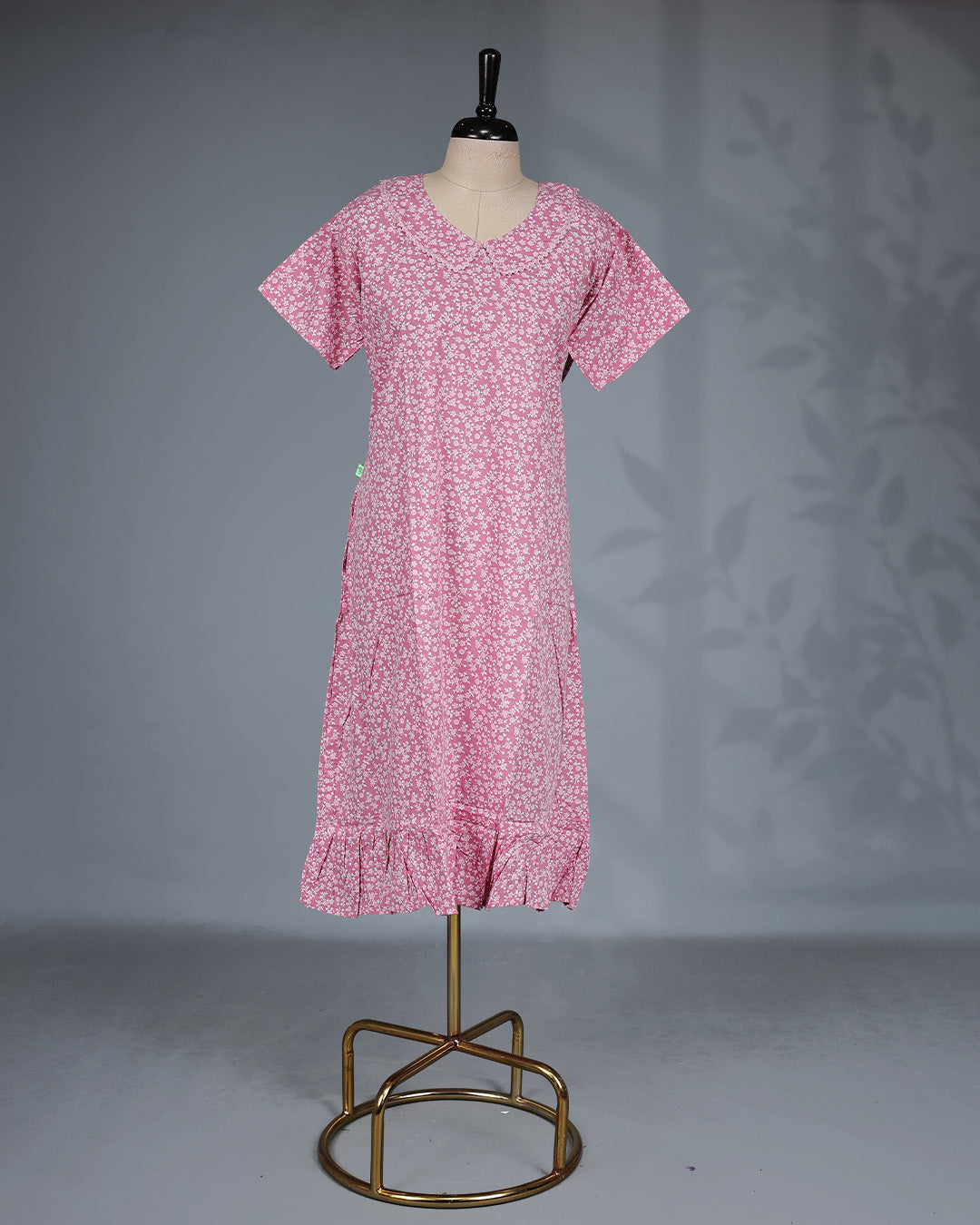 Blush pink colour nighty featuring white floral prints ob body, a U Shaped neckline with lace-trimmed Peter Pan collar, short sleeves, and a ruffled Mid-length fit