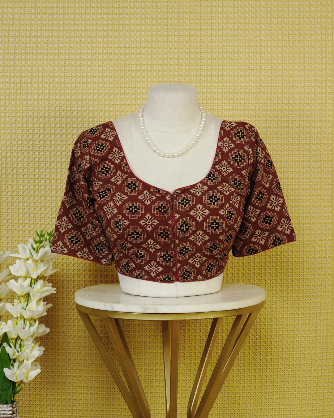 Maroon Colour Printed Blouse Featuring An All Over Geometric Floral Motif, Enhanced With A Round Neckline, Front Button Closure, And Elbow Length Sleeves.