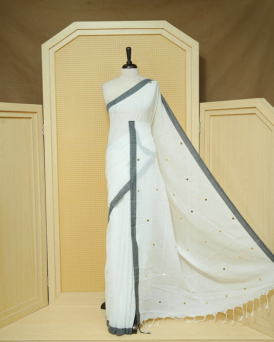 White colour Mul cotton saree featuring Gold Sequins, complemented by Contrast Black simple Border & tassels.