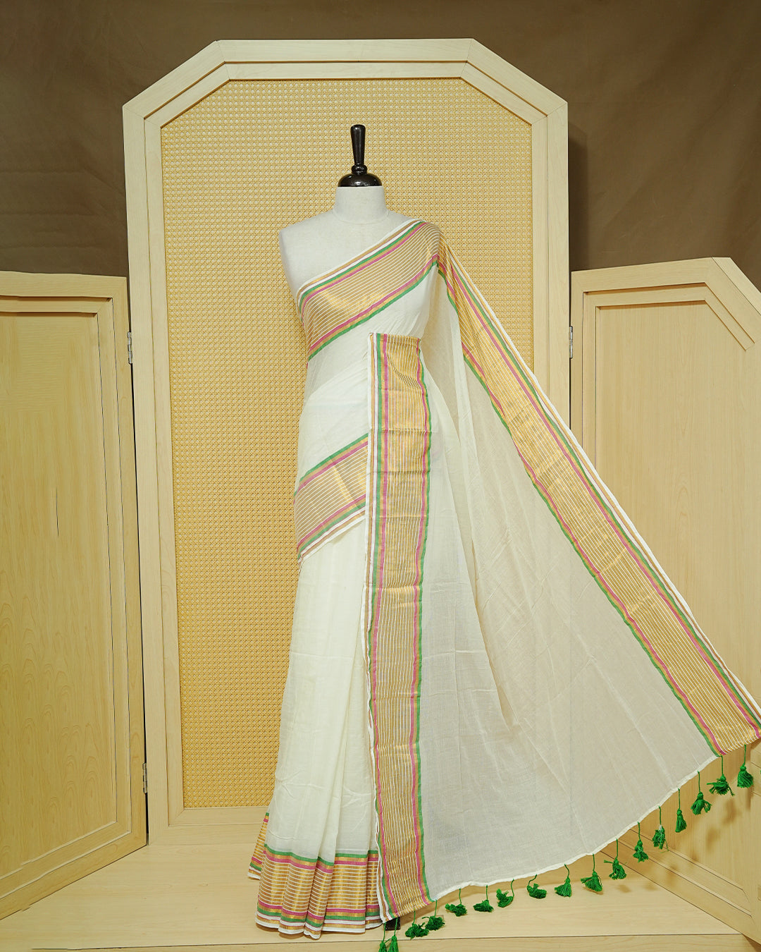 Off White Mul Cotton Saree featuring a gold zari striped border with pink and green accents, paired with a pallu and finished with green tassels.