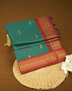 Peacock Green Colour Kalyani cotton saree featuring elegant antique zari peacock butta motifs on the body, complemented by a Maroon contrast pallu with a rich antique zari border, paired with a matching blouse piece