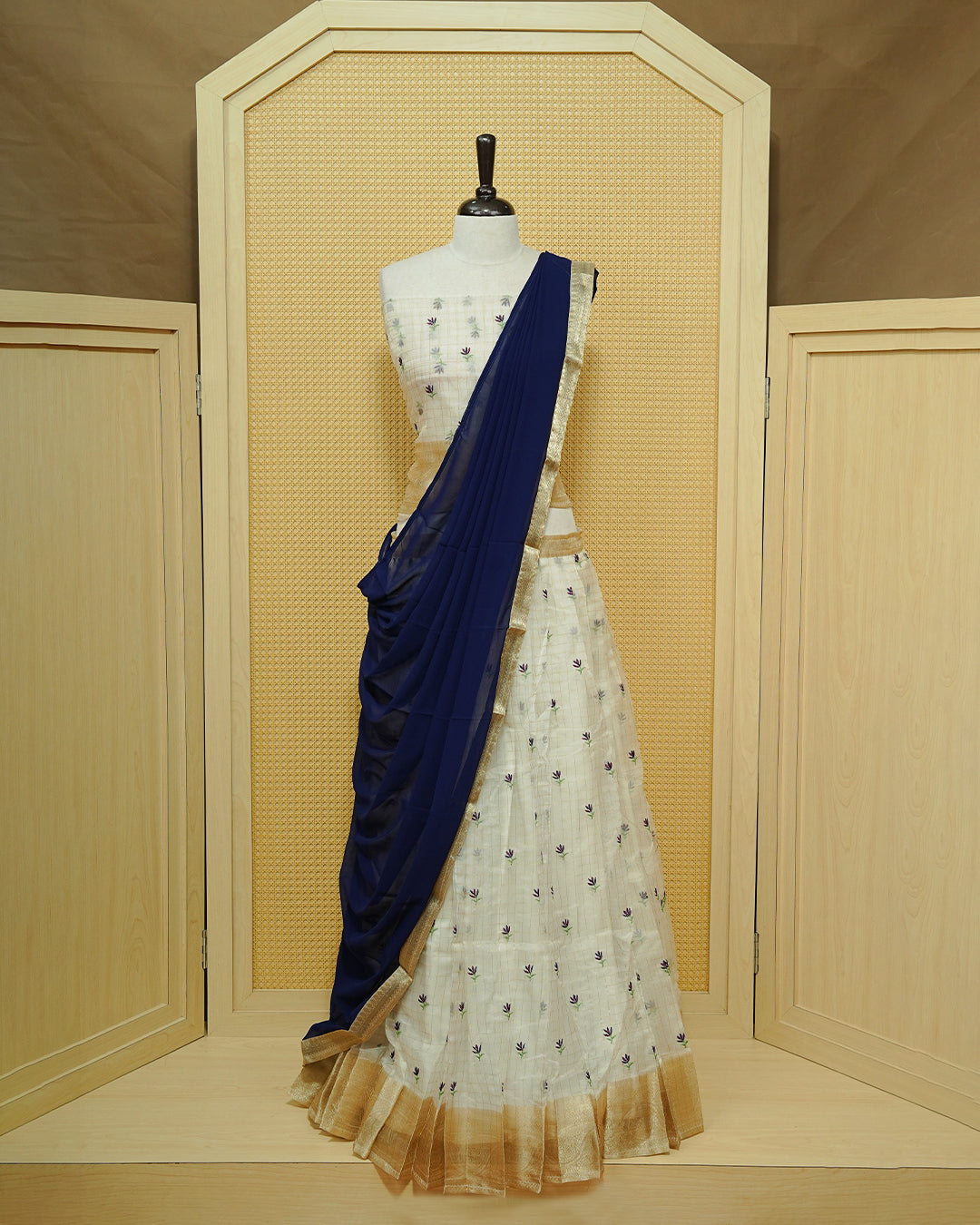 Cream colour Semi stitched Dhavani set featuring Gold zari checked pattern with floral motifs on skirt with traditional border, comes with contrast Colour Dupatta & matching blouse piece.