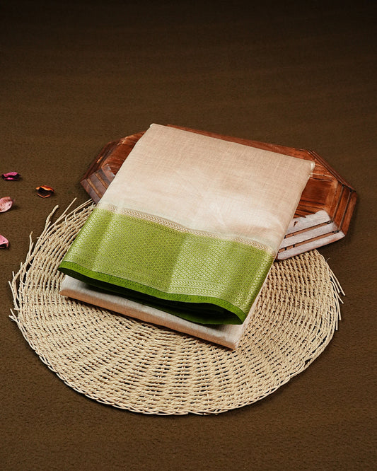 Light gold colour Semi Tussar silk saree featuring an elegant plain body, accentuated by a contrast Light green border adorned with intricate gold zari work, paired with a matching blouse piece.