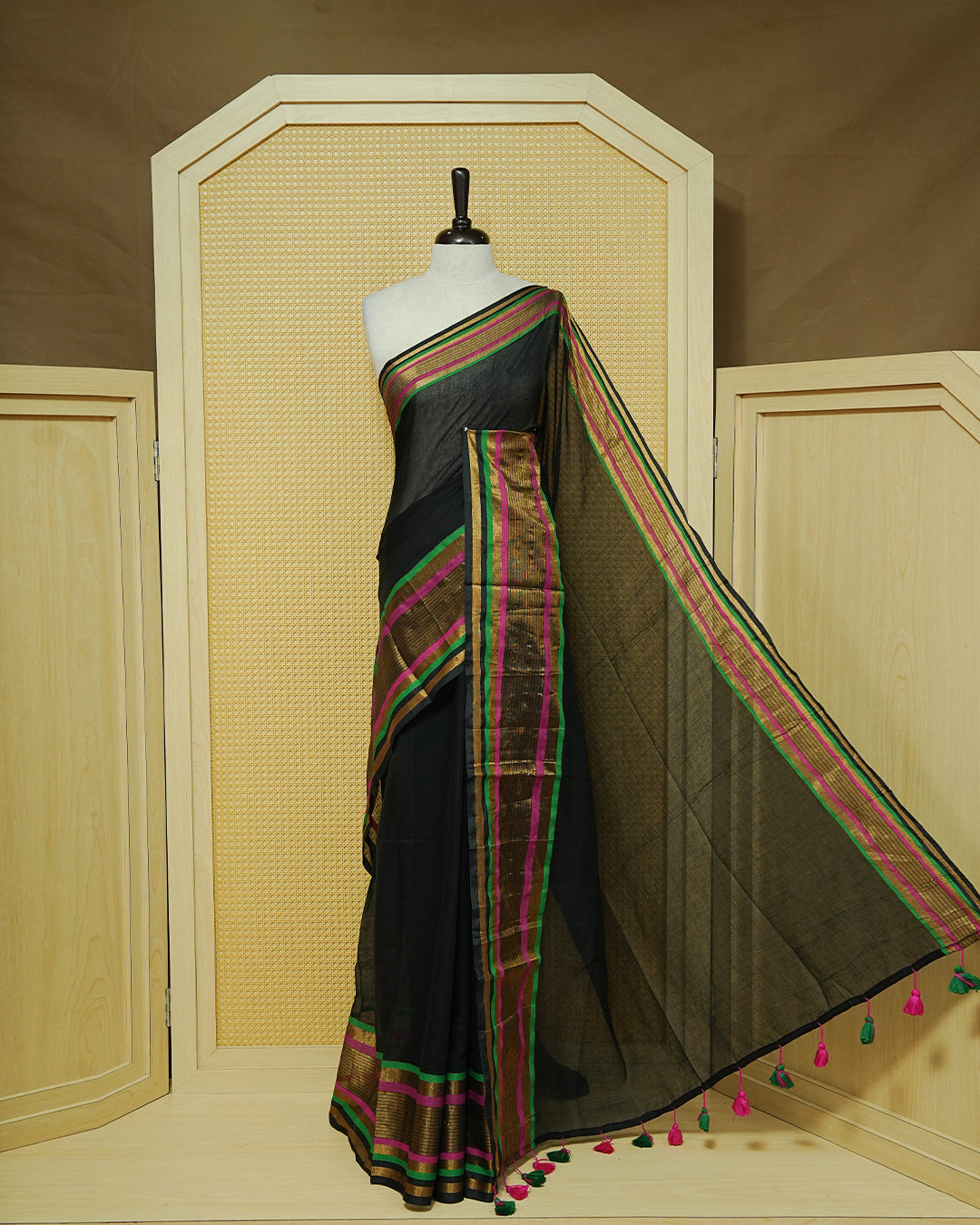 Black Mul Cotton Saree featuring a plain black body with a multicolour striped zari border in magenta, green, and gold, finished with dual-tone magenta and green tassels.