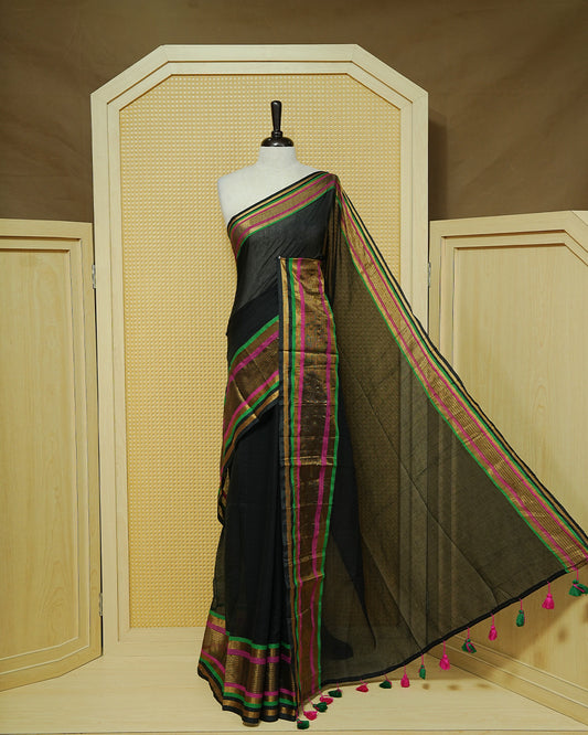 Black Mul Cotton Saree featuring a plain black body with a multicolour striped zari border in magenta, green, and gold, finished with dual-tone magenta and green tassels.
