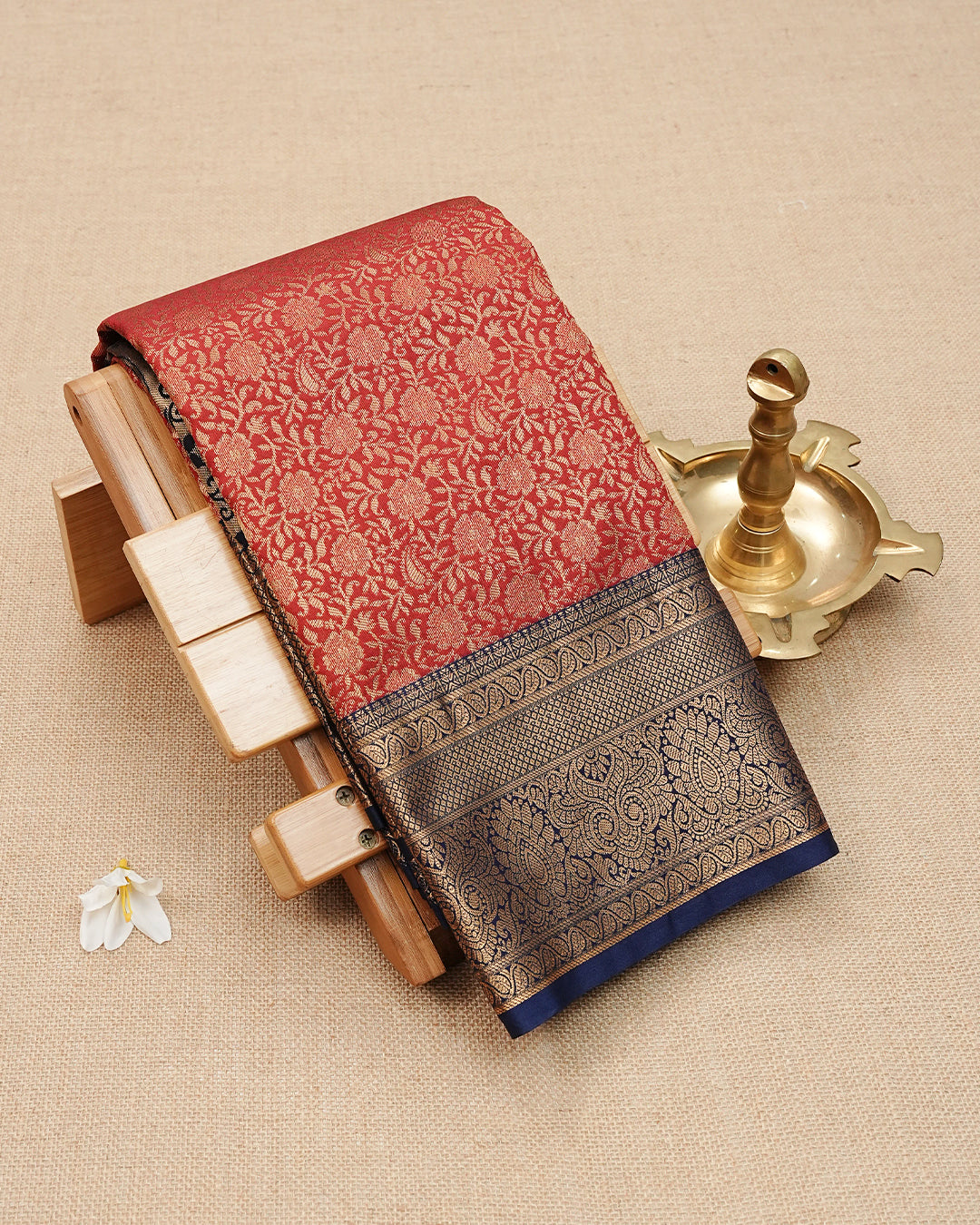 Dark Brick Red colour semi wedding saree featuring  gold zari Floral kodi  Pattern on body, contrast  Navy blue colour with traditional border, paired with matching blouse piece.