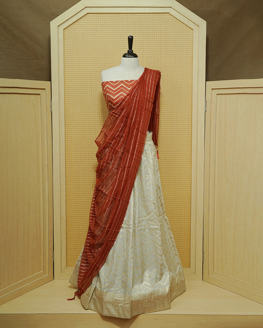Cream colour Semi Stitched Dhavani set Featuring Gold zari Zigzag pattern With Traditional border skirt, Contrast Red colour Dupatta, Matching blouse piece.