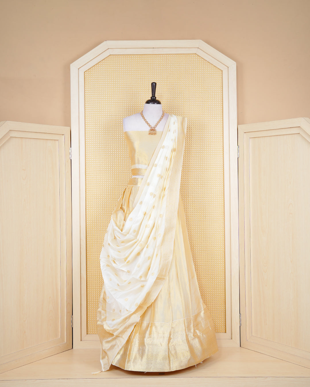Cream coloured tissue semi stitched dhavani set featuring gold zari Motifs on the body with a matching gold zari bordered skirt & blouse piece and dupatta.
