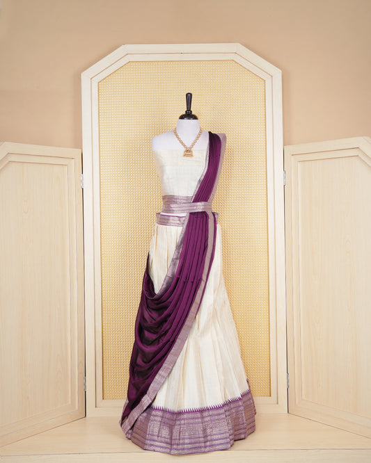 Cream colour tissue Semi stitched dhavani set featuring Gold zari check pattern with motifs on body ,contrast Purple colour with gold zari bordered skirt, paired with matching blouse piece & dupatta.