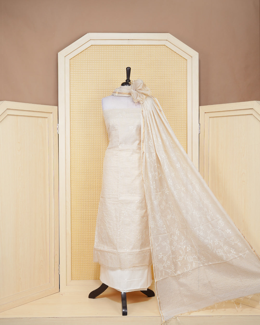 Cream colour tissue salwar material featuring gold zari checked pattern with elegant floral threadwork pattern on the body, paired with a matching bottom and an elegant dupatta.