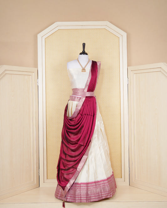 Cream colour  tissue Semi stitched dhavani set featuring Gold zari check pattern with motifs on body ,contrast Brick Red colour with gold zari bordered skirt, paired with matching blouse piece & dupatta.