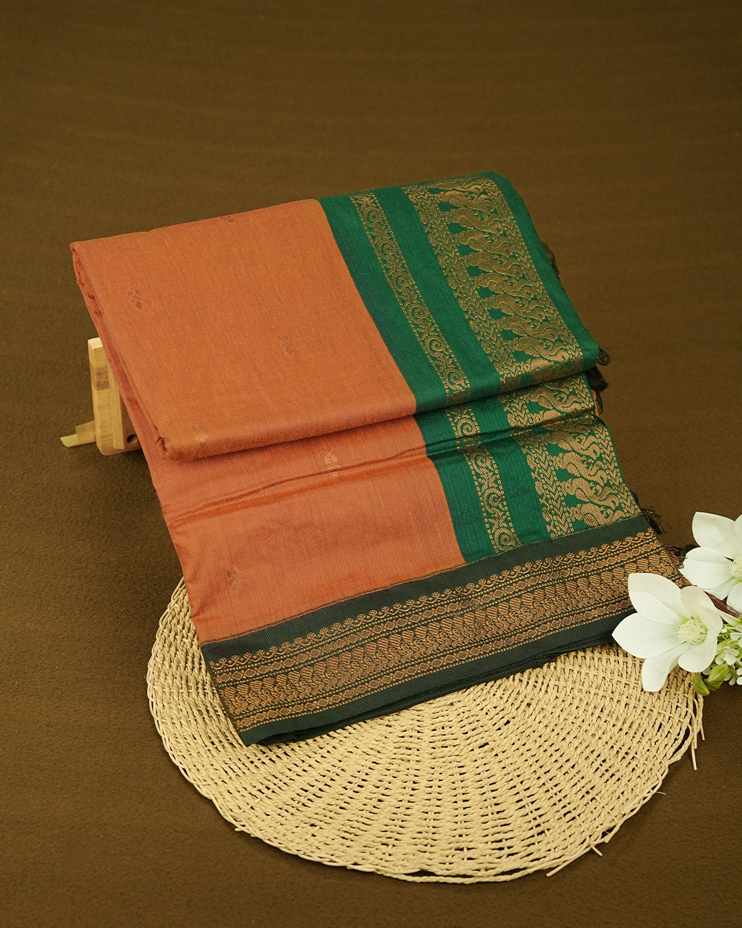 Orange  colour kalyani cotton saree featuring gold zari Motifs on body, complemented by Green colour with Gold zari border, paired with matching blouse piece