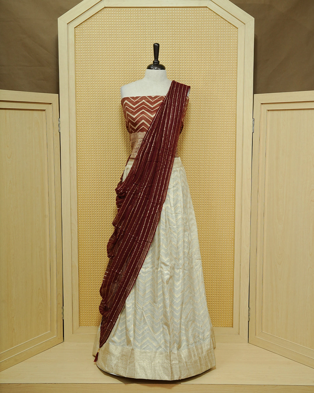 Cream colour Semi Stitched Dhavani set Featuring Gold zari Zigzag pattern With Traditional border skirt, Contrast Maroon colour Dupatta, Matching blouse piece.