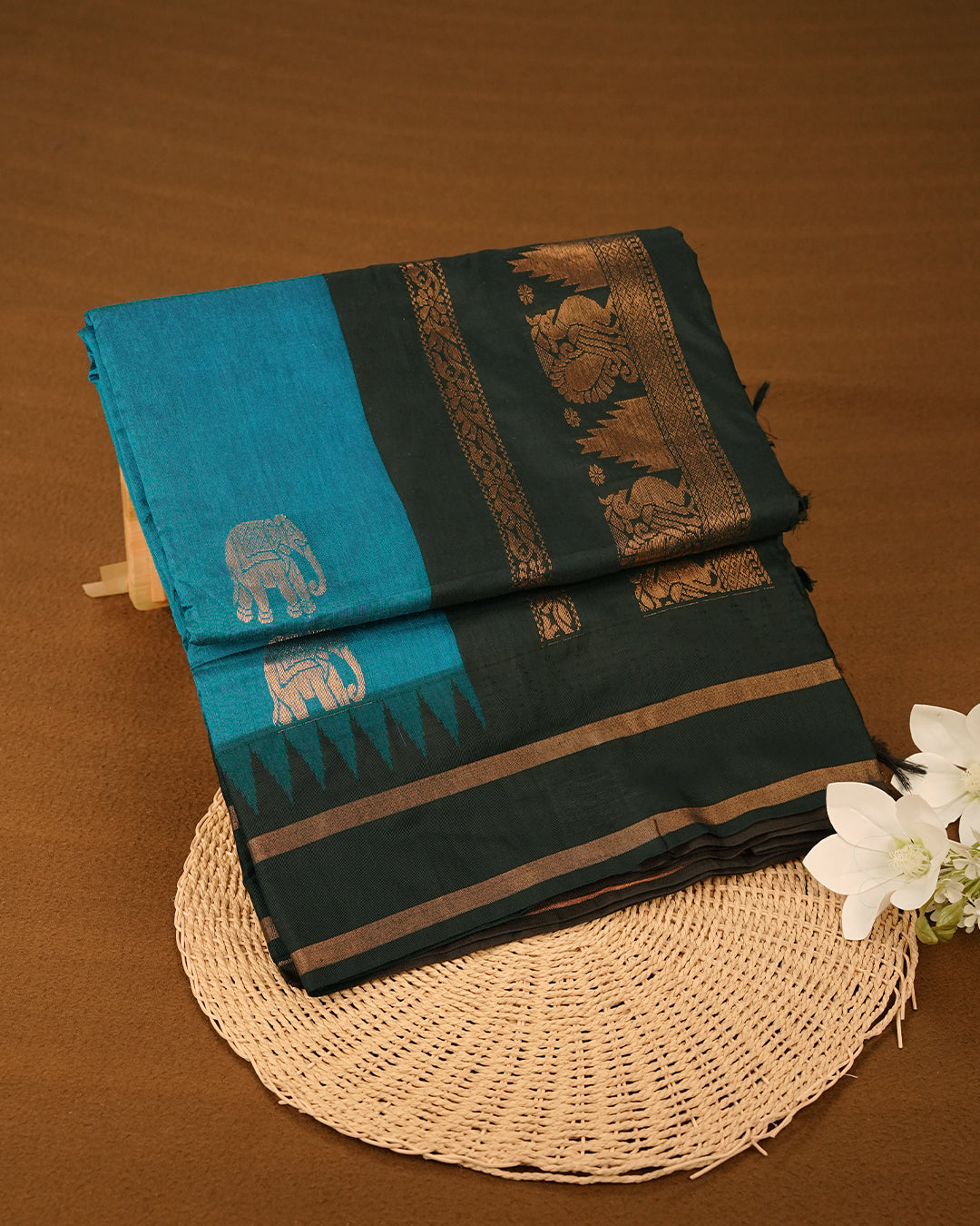 Turquoise Blue Colour Kalyani cotton saree featuring elegant antique zari elephant and floral motifs on the body, complemented by a Black contrast pallu with a rich antique zari peacock border, paired with a matching Black blouse piece.
