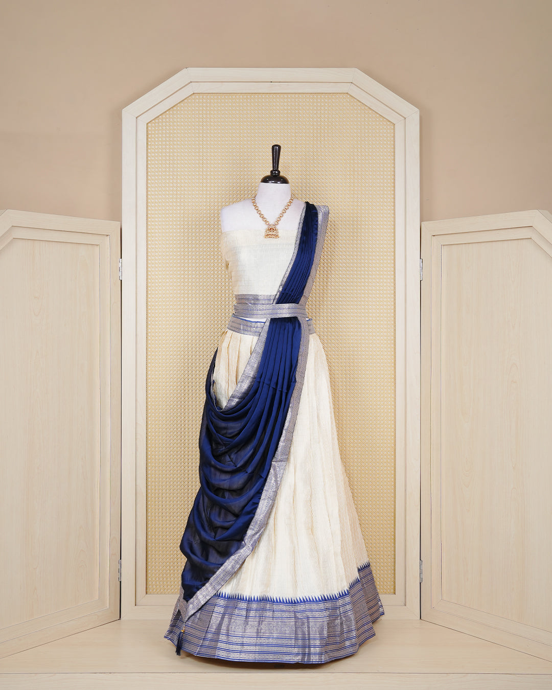 Cream colour tissue Semi stitched dhavani set featuring Gold zari check pattern with motifs on body ,contrast Blue colour with gold zari bordered skirt, paired with matching blouse piece & dupatta.