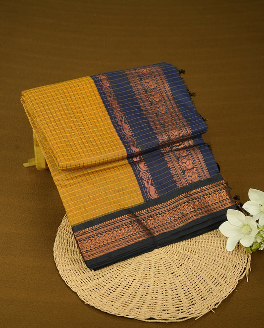 Mustard colour kalyani cotton saree featuring Copper zari check pattern on body, complemented by Navy Blue colour with Antique Copper zari border, paired with matching blouse piece