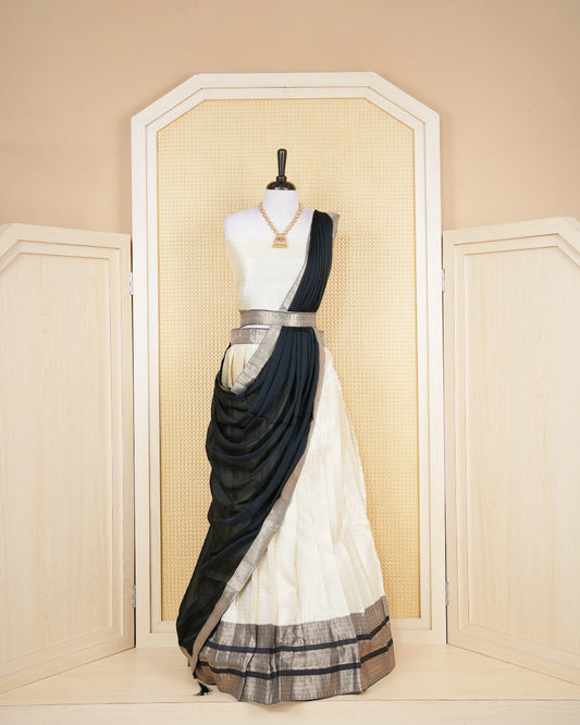 Cream colour tissue Semi stitched dhavani set featuring Gold zari check pattern with motifs on body ,contrast Black colour with gold zari bordered skirt, paired with matching blouse piece & dupatta.