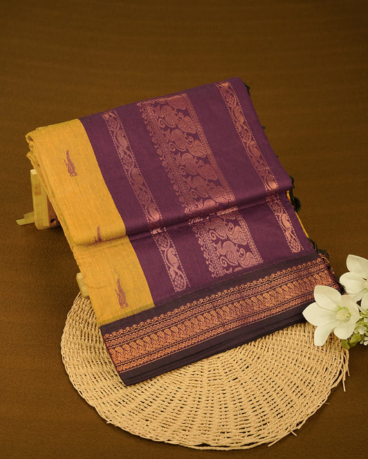 Mustard Yelow colour kalyani cotton saree featuring Grape Colour Peacock pattern on body, complemented by Grape with Grand Copper Zari border, paired with matching blouse piece