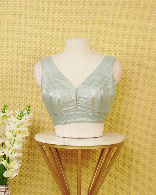 ice Blue colour Sleeveless Blouse Featuring A Stylish V-Neck, Elegant Woven Zari Stripes With Butta Motifs, And A Comfortable Tailored Fit.