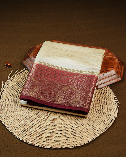 Light gold tussar saree featuring Elegant plain body, complemented by contrast Maroon colour with Gold zari Floral kodi with Peacock Pattern border, comes with matching blouse piece.