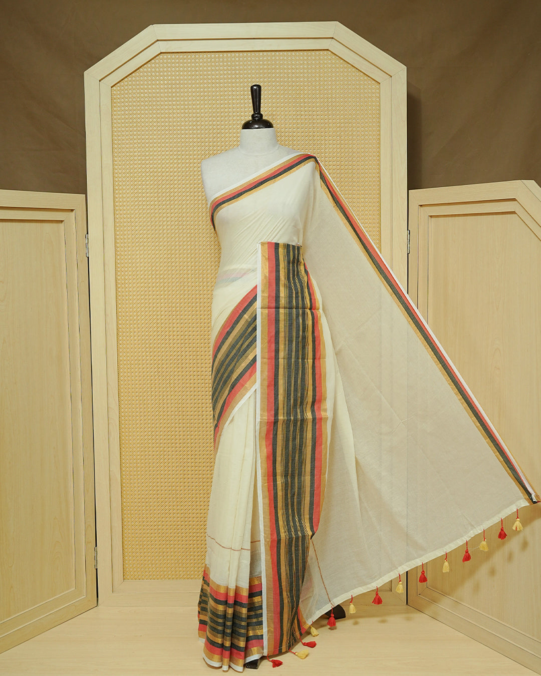 Cream colour Mul cotton saree featuring Elegant Plain body, complemented by contrast Red, Black & gold zari border & Tassels.