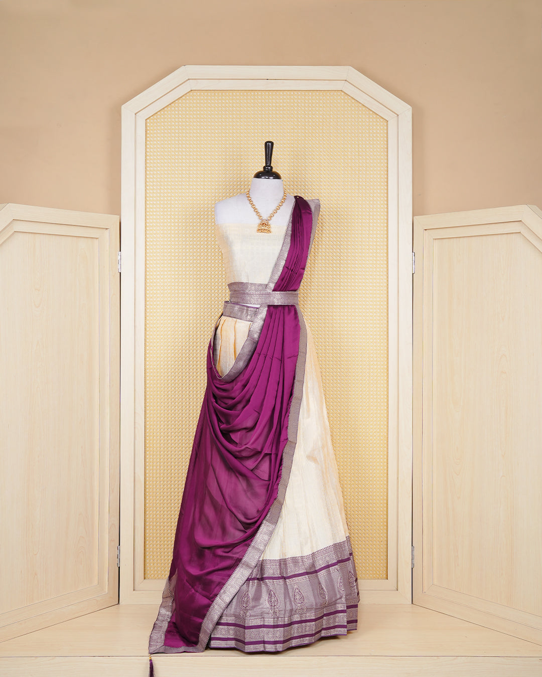 Cream colour  tissue  Semi stitched dhavani set featuring Gold zari check pattern on body ,contrast Purple colour with gold zari bordered skirt, paired with matching blouse piece & dupatta.
