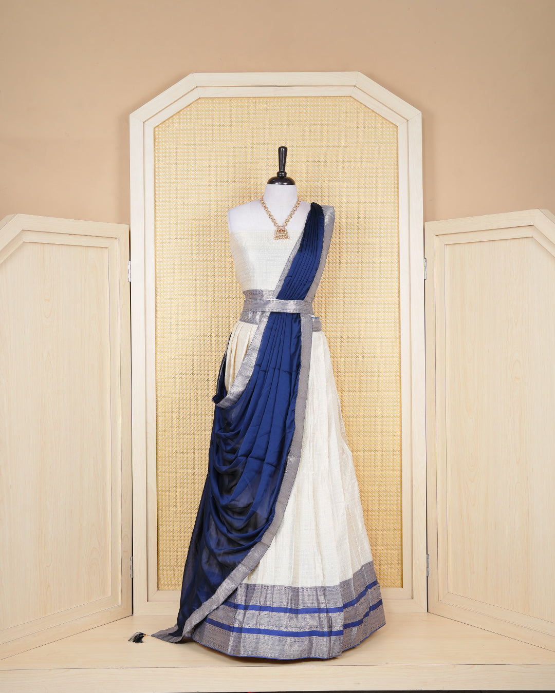 Cream colour tissue Semi stitched dhavani set featuring Gold zari check pattern with motifs on body ,contrast Blue colour with gold zari bordered skirt, paired with matching blouse piece & dupatta.