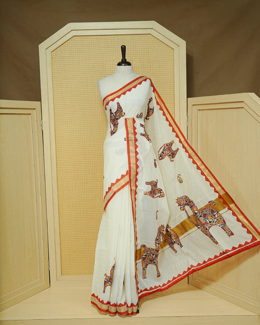Cream colour Kerala saree Featuring Ajrakh Inspired Buttas Red Horse pattern, Gold zari border, comes with matching blouse piece.