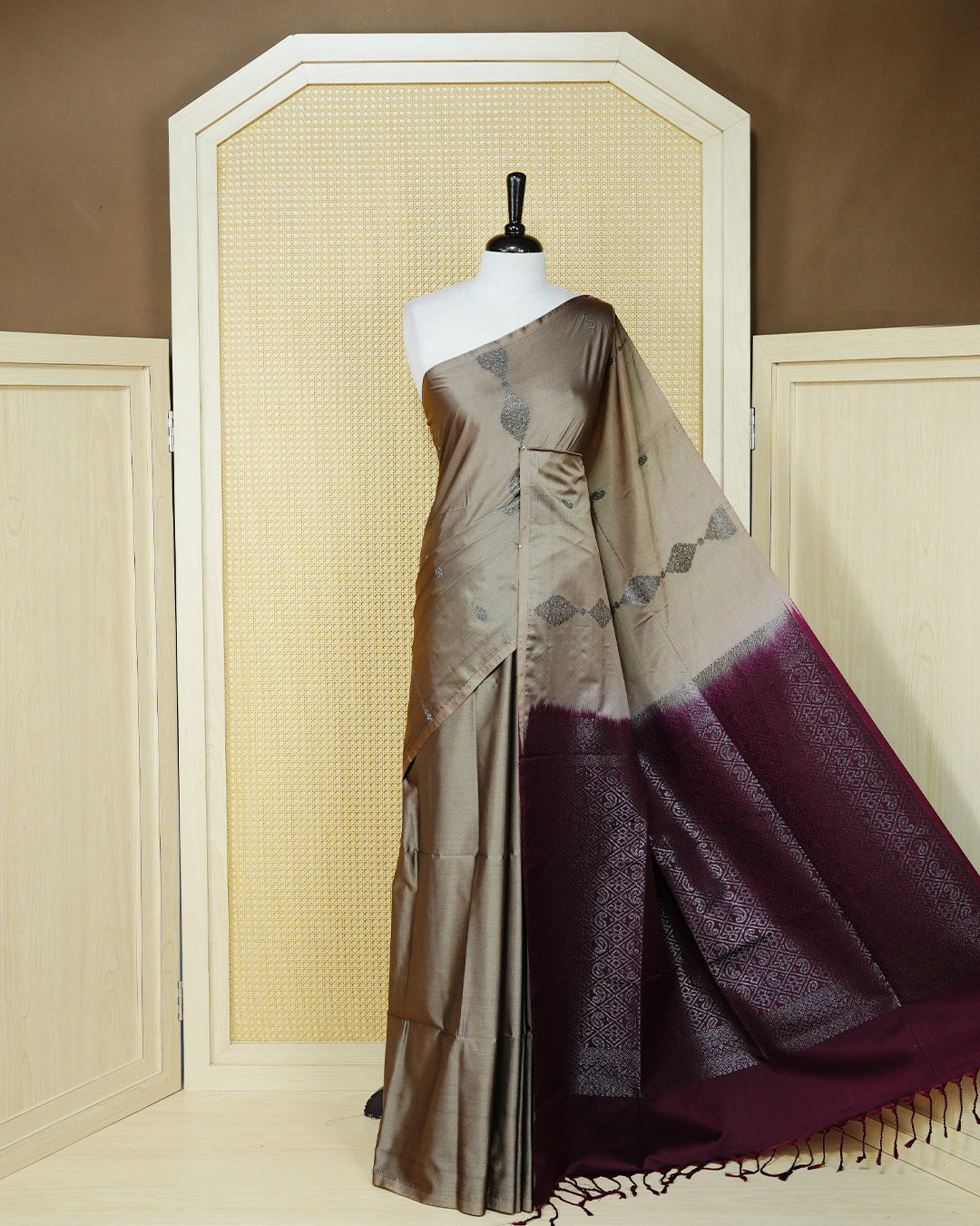 Taupe beige colour soft silk saree featuring antique zari motifs on body with contrast dark maroon colour pallu & paired with matching blouse piece.