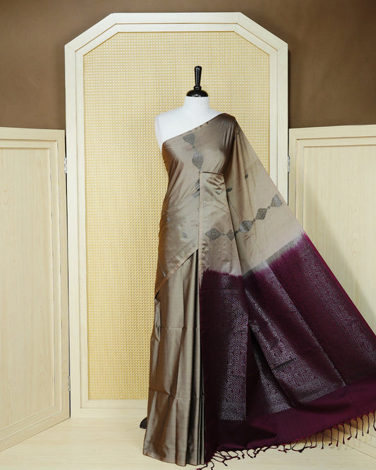 Taupe beige colour soft silk saree featuring antique zari motifs on body with contrast dark maroon colour pallu & paired with matching blouse piece.