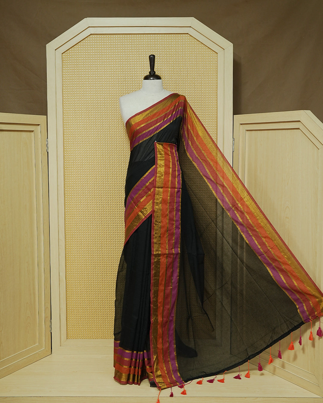 Black  Colour Mul Cotton Saree with a plain black body and a multicolour zari striped border in rust, magenta, and gold & Magenta , Orange Tassels