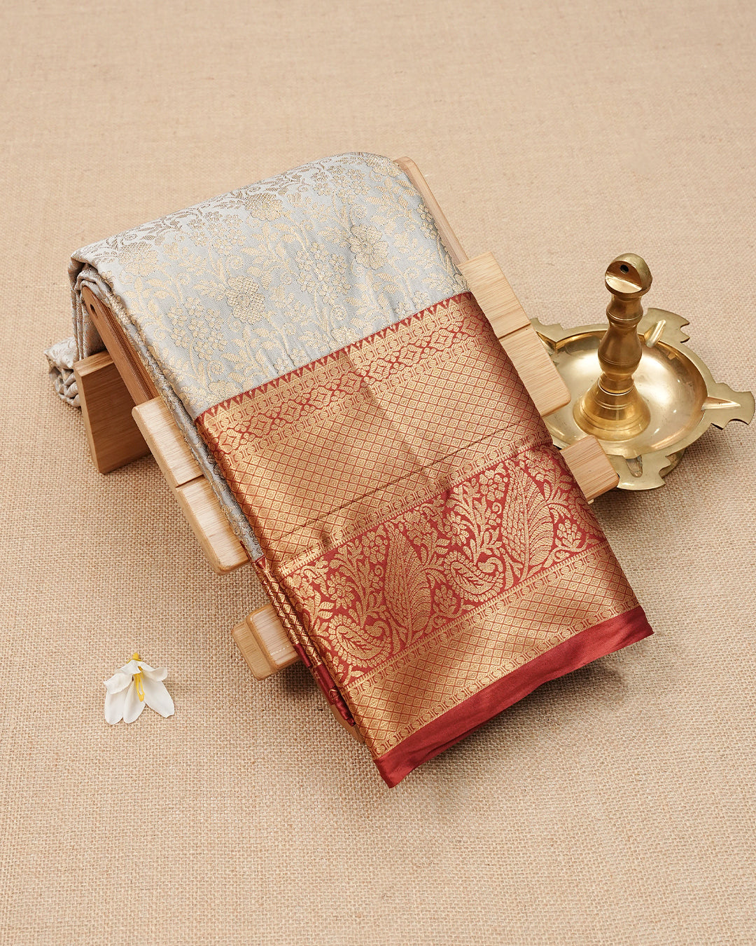 Cream colour semi wedding saree featuring  gold zari Floral kodi  Pattern on body, contrast  Dark Crimson red colour with traditional border, paired with matching blouse piece.