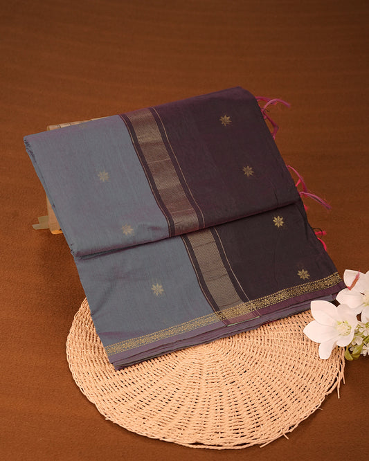 Bluish Grey Colour Kalyani Cotton Saree Featuring Gold Zari Floral Patterns on the Body, Complemented by a Dark Wine Colour Border with Stripes & Floral Gold Zari, Paired with a Matching Blouse Piece.