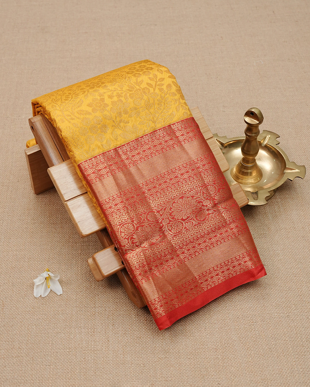 Mustard Yellow colour semi wedding saree featuring  gold zari  Floral Kodi Pattern on body, contrast  Red colour with traditional border, paired with matching blouse piece.