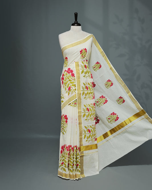 Cream colour Cotton kerala saree featuring Magenta colour floral Print on the body, complemented by a gold zari Border, paired with a matching blouse piece.