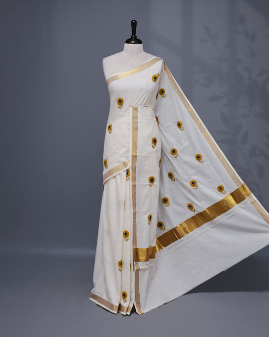 Cream colour Cotton kerala saree featuring Sunflower Embroidery work on the body, complemented by a gold zari Border, paired with a matching blouse piece.