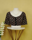Black Colour Printed Blouse Featuring An All Over Geometric Floral Motif, Enhanced With A Round Neckline, Front Button Closure, And Elbow Length Sleeves.