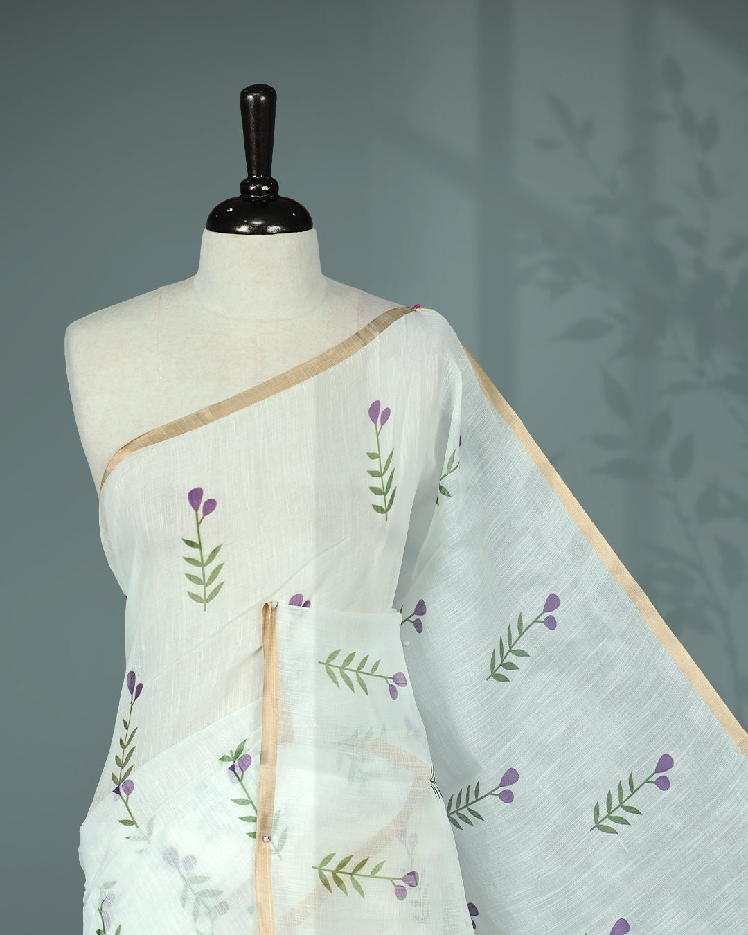 Off-white linen saree featuring beautiful Purple floral and leafy prints on the body, complemented by a tissue piping border and a contrasting pallu. Paired with a matching blouse piece.