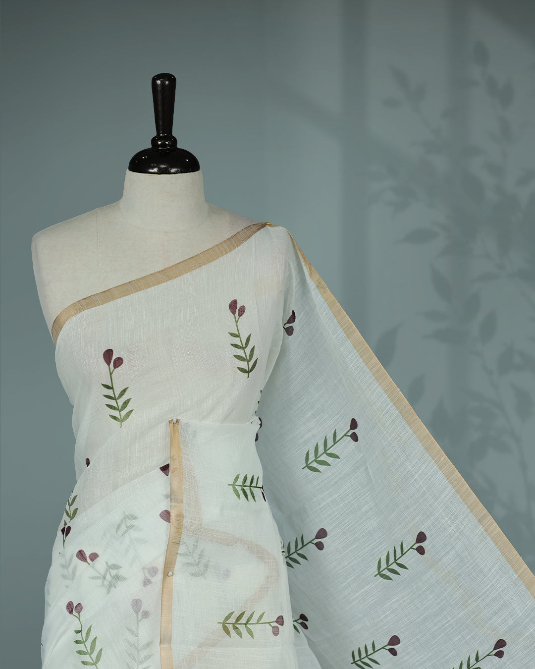 Off-white linen saree featuring beautiful Brown floral and leafy prints on the body, complemented by a tissue piping border and a contrasting pallu. Paired with a matching blouse piece.