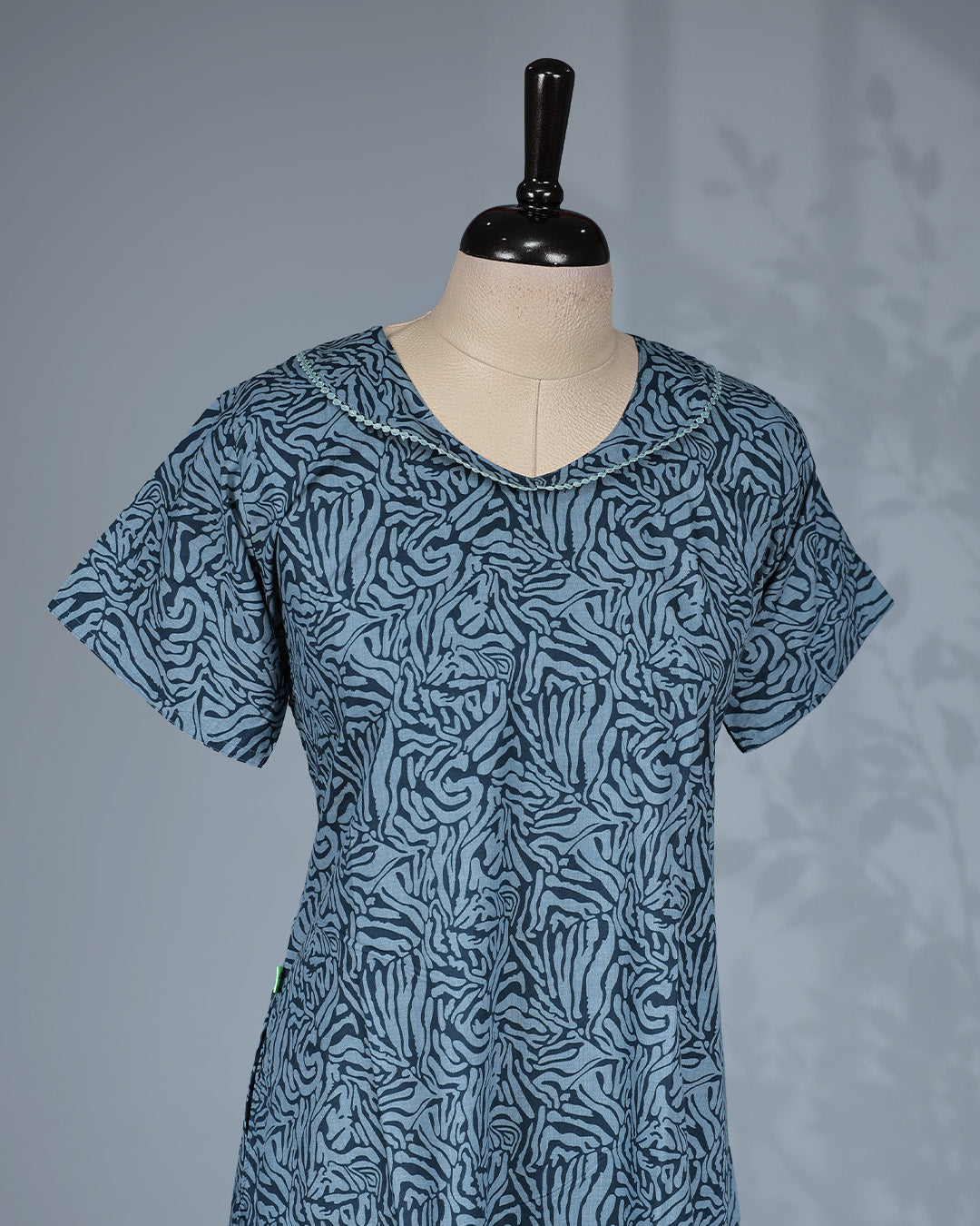 Greish Blue colour printed nighty featuring a graceful U-neckline with delicate lace trim, short sleeves and Mid-lenght fit.