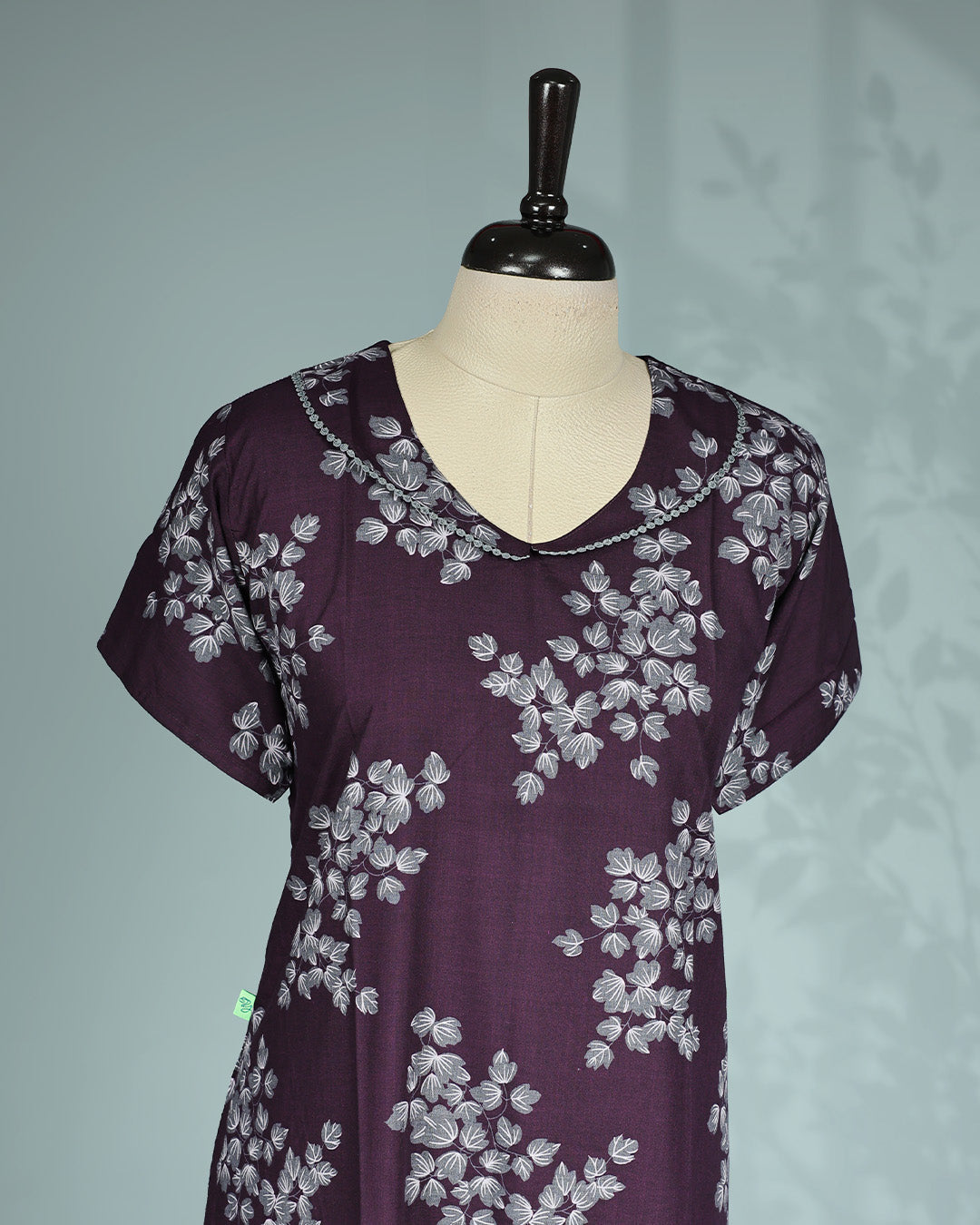 Dark Purple colour nighty featuring white floral prints on body, a round neckline with lace trim, short sleeves, and a ruffled mid-length fit