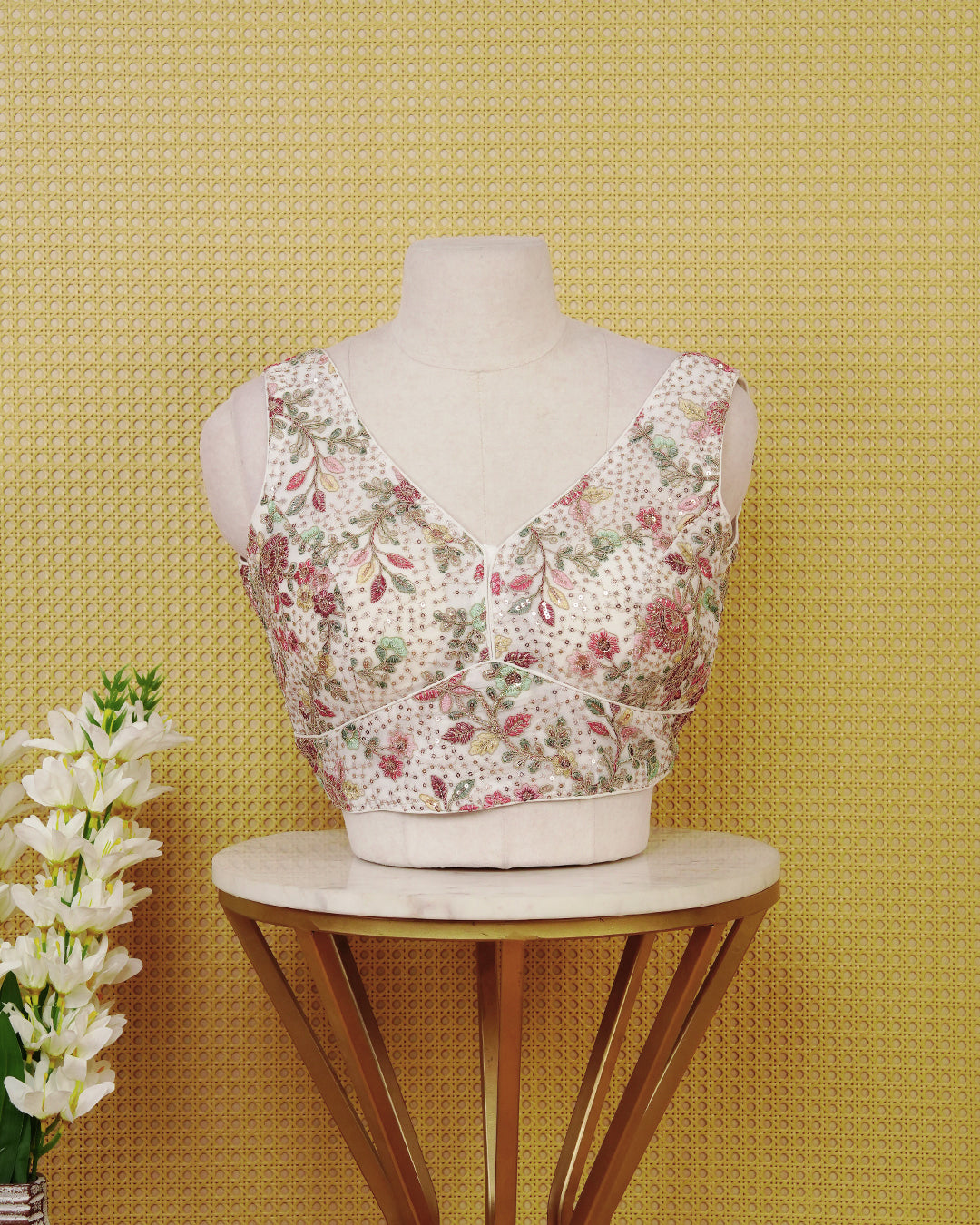 Off White colour Embroidered Sleeveless Blouse Featuring A Stylish V-Neck, Intricate Floral Embroidery With Sequin Detailing, And A Comfortable Tailored Fit.